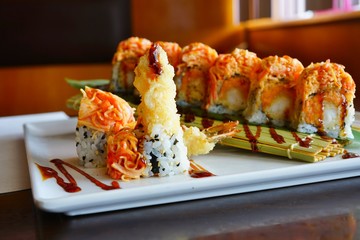 A plate of fried shrimp tempura and spicy crab sushi roll with eel sauce at a Japanese restaurant