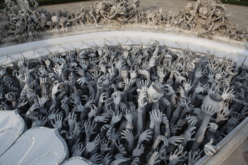 Hands of people pulled with entreaty. Wat Rong Khun (White Temple) in Chiang Rai city, Thailand. Religious traditional national Thai architecture. Landmark, architectural monument of Chiang Rai. Money - obrazy, fototapety, plakaty