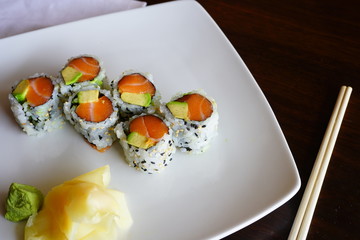 A plate of avocado and salmon sushi roll with pickled ginger and wasabi at a Japanese restaurant