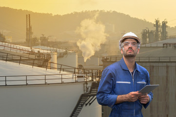 Caucasian man engineer staff worker with tablet in hand and refinery background concept.