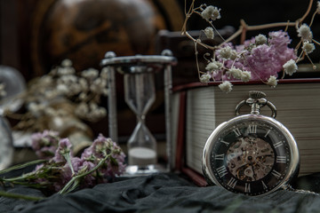 Pocket watch, blur stack of old book, hourglass, vintage binocular and world desk globe on dark background.