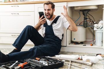 Negative man plumber work in uniform indoors