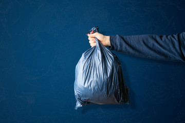 hand holding the  dark blue trash bag, concept of cleaning earth planet,isolated against the...