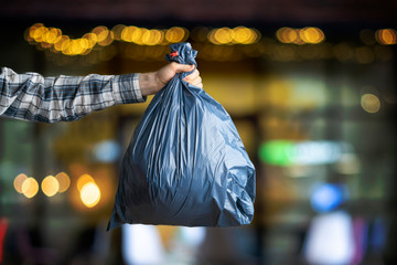 hand holding the  dark blue trash bag, concept of cleaning earth planet