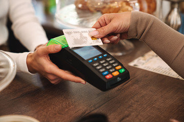 Cropped photo of mature woman paying credit card in cafe