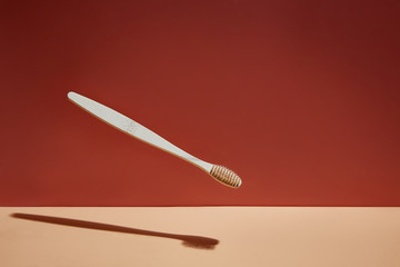 Wooden biodegradable bamboo toothbrush drops on a colored background. Health, environment and zero waste concept.