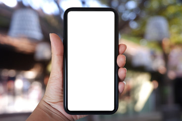 Close-up hand holding phone vertical, Using smart phone with blurred background of house, cafe interior - copy space