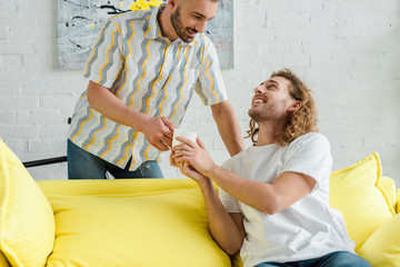 happy homosexual men holding cup of tea at home