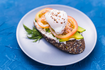 Sandwich with smoked salmon, egg and avocado on blue background, top view. Concept for healthy nutrition.