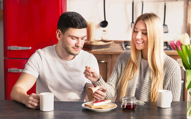 Woman helping her husband to spread jam on sandwich
