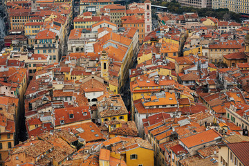 Fototapeta na wymiar Panoramic top view over the Nice city with atmospheric traditional houses with red tiled roofs. Picturesque view from the viewing ground of Château hill to the on the old city of Nice, France. 