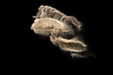 Brown colored sand splash.Dry river sand explosion isolated on black background. Abstract sand...