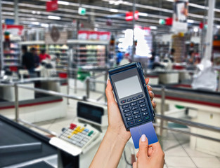 Payment of purchases in the supermarket. Modern payment blue terminal and card.