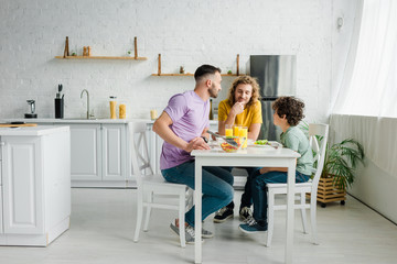 homosexual parents and cute mixed race son having lunch at home