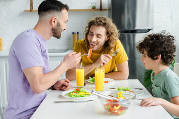 happy homosexual men having salad with mixed race son