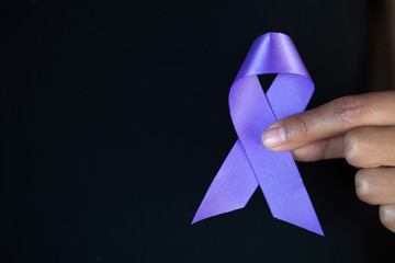 Woman Hand Holding Purple Ribbon, Domestic Violence Awareness Month (October) concept with deep...