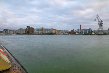 Fototapeta premium City working area, cargo port with cranes on the seashore. Helsinki panorama, Finland - February 18, 2020: Lautasaari island in cloudy weather. Early morning.