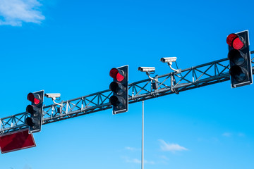 Red traffic lights and cameras againts blue skies