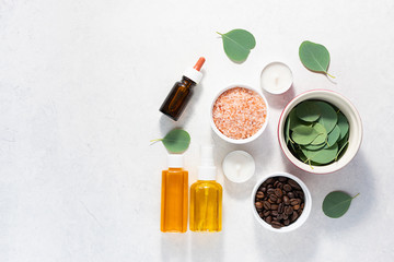 Fresh organic ingredients for homemade skin care products. Spa and wellness concept. Himalaya salt, eucalyptus leaves, essential oils and coffee beans on white marble table top view.