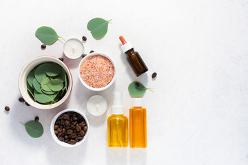Fresh organic ingredients for homemade skin care products. Spa and wellness concept. Himalaya salt, eucalyptus leaves, essential oils and coffee beans on white marble table top view.