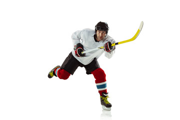 Scoring. Young male hockey player with the stick on ice court and white background. Sportsman...