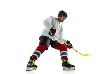 Attented. Young male hockey player with the stick on ice court and white background. Sportsman wearing equipment and helmet practicing. Concept of sport, healthy lifestyle, motion, movement, action.
