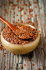 Flax seeds in a bowl on a wooden background close-up.