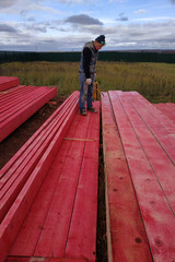 Worker covers wooden boards with protective paint.