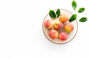 Summer fruits. Ripe red peaches on plate on white table top-down copy space
