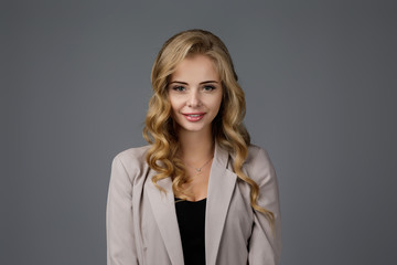 smiling happy young business woman looking at camera on gray background.