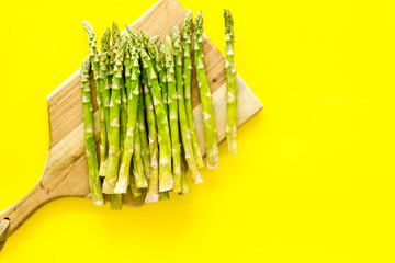 Cooking asparagus. Fresh steams on cutting board on yellow background top-down copy space