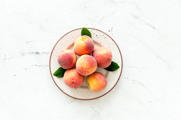 Summer fruits. Ripe red peaches on plate on white table top-down copy space
