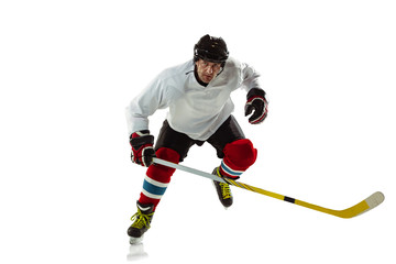 Character. Young male hockey player with the stick on ice court and white background. Sportsman wearing equipment and helmet practicing. Concept of sport, healthy lifestyle, motion, movement, action.