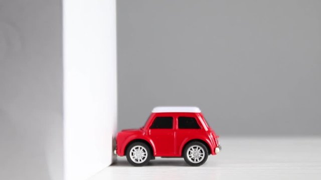 Crash Test Automotive Vehicle Wall. A Small Red Model Car Crashes Into A Building Wall.