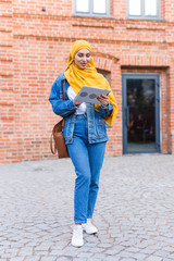 Arab woman student. Beautiful muslim female student wearing bright yellow hijab holding tablet.