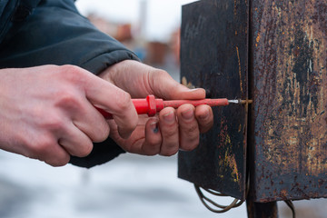 worker opens a rusty old batch switch. unscrews with a red screwdriver the bolt that holds the...