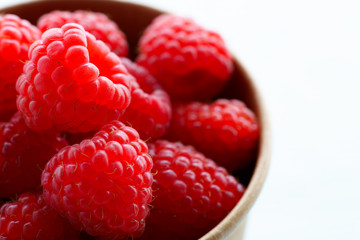 Freshly picked organic raspberries in recycled paper cup. High resolution, white background