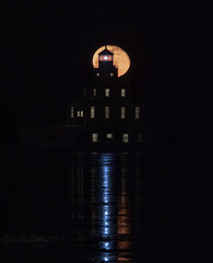 Moon rising behind a lighthouse - 324271922