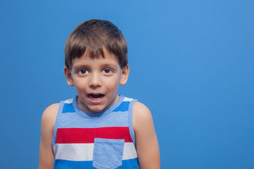 a young boy in a striped t-shirt poses as a model on a blue background