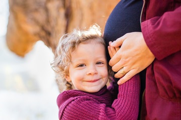 Young girl with her hands on her mother's pregnant belly
