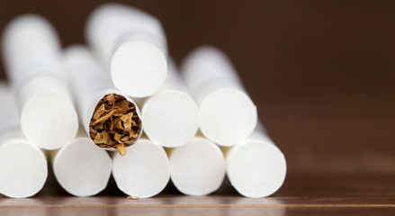 Closeup web banner of rolled cigarettes on brown background, smoking concept