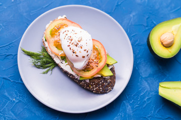 Sandwich with smoked salmon, egg and avocado on blue background, top view. Concept for healthy nutrition.