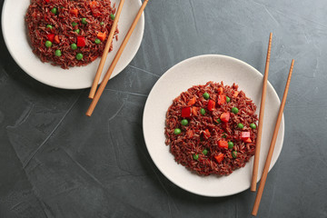 Tasty brown rice with vegetables on dark grey table, flat lay