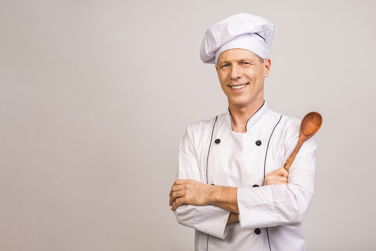 Smiling senior male chef isolated over white background.