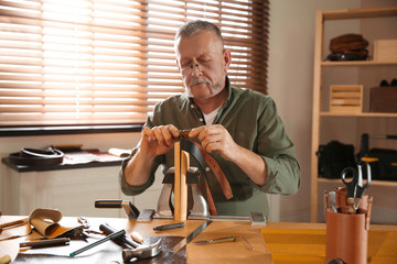 Man burnishing edges of leather belt in workshop