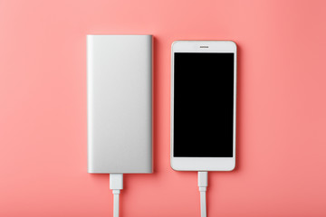 Powerbank charges a smartphone on a pink background. Universal external battery for gadgets Free...
