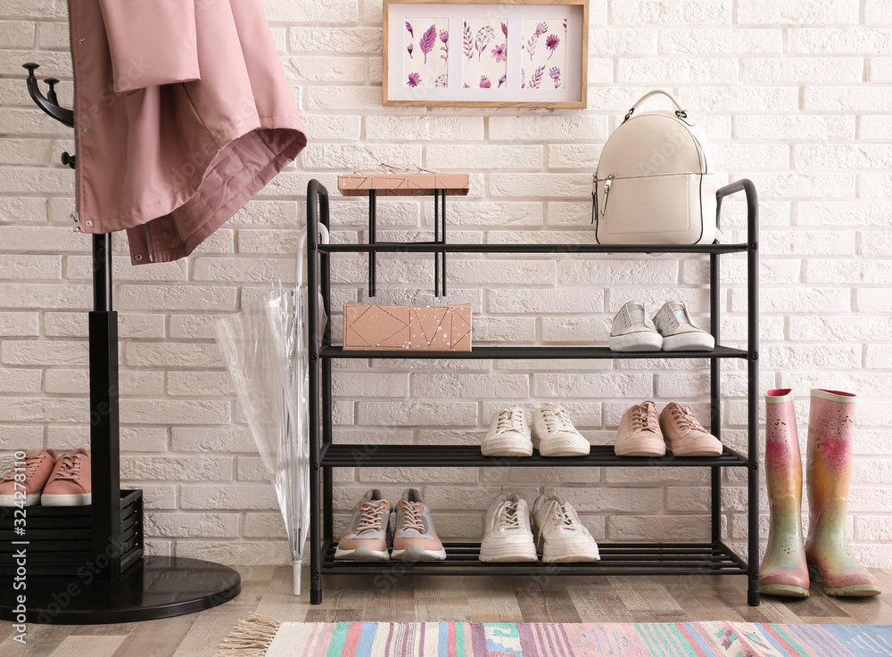 Poster Shelving rack with stylish women's shoes and accessories near white brick wall indoors