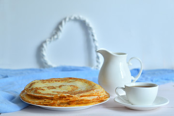 Pancake week: thin pancakes with jug and tea on white table.french crepes .thin pancakes and glass of milk on the table.Delicious breakfast.Selective focus
