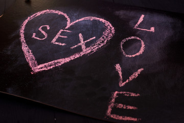 Heart and sex drawn on a black background. The concept of love and the relationship between the sexes.