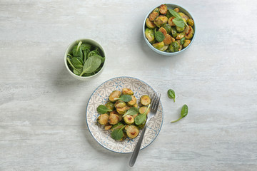 Delicious roasted brussels sprouts with basil served on white wooden table, flat lay